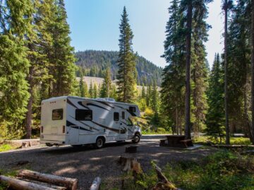 Beautiful campsite in the mountains with an RV and wooden bench. beautiful campsite mountains with rv wooden bench scaled