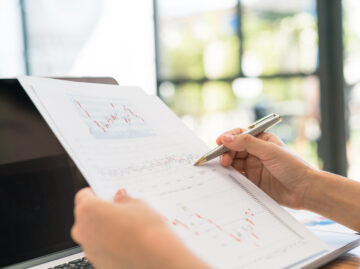 business woman hand with financial charts laptop table