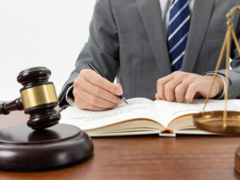 Versicherer begrüßen Themensetzung im Koalitionsvertrag 4 closeup shot person writing book with gavel table 1 scaled