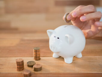 hand inserting coin piggy bank scaled