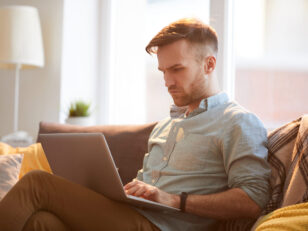 handsome man using laptop home scaled