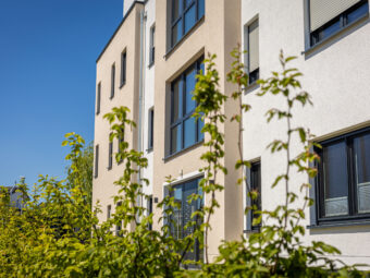 modern residential building exterior with green foliage clear blue sky scaled
