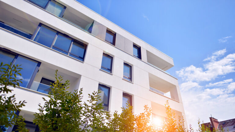 building with blue sky trees background scaled