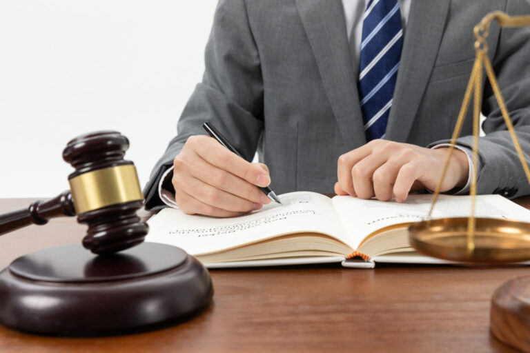 closeup shot person writing book with gavel table 1 scaled