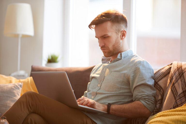 handsome man using laptop home scaled